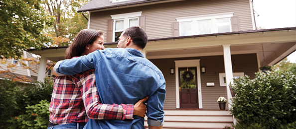  A young man and woman embrace in front of their energy-efficient house.